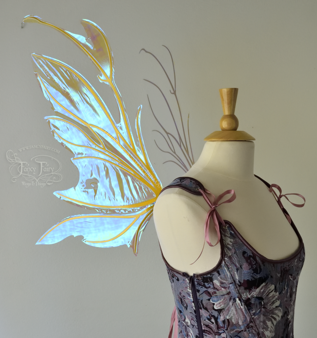 Transparent blue / green iridescent fairy wings with antennae and tattered holes with gold veins, worn on a dress form, left side view