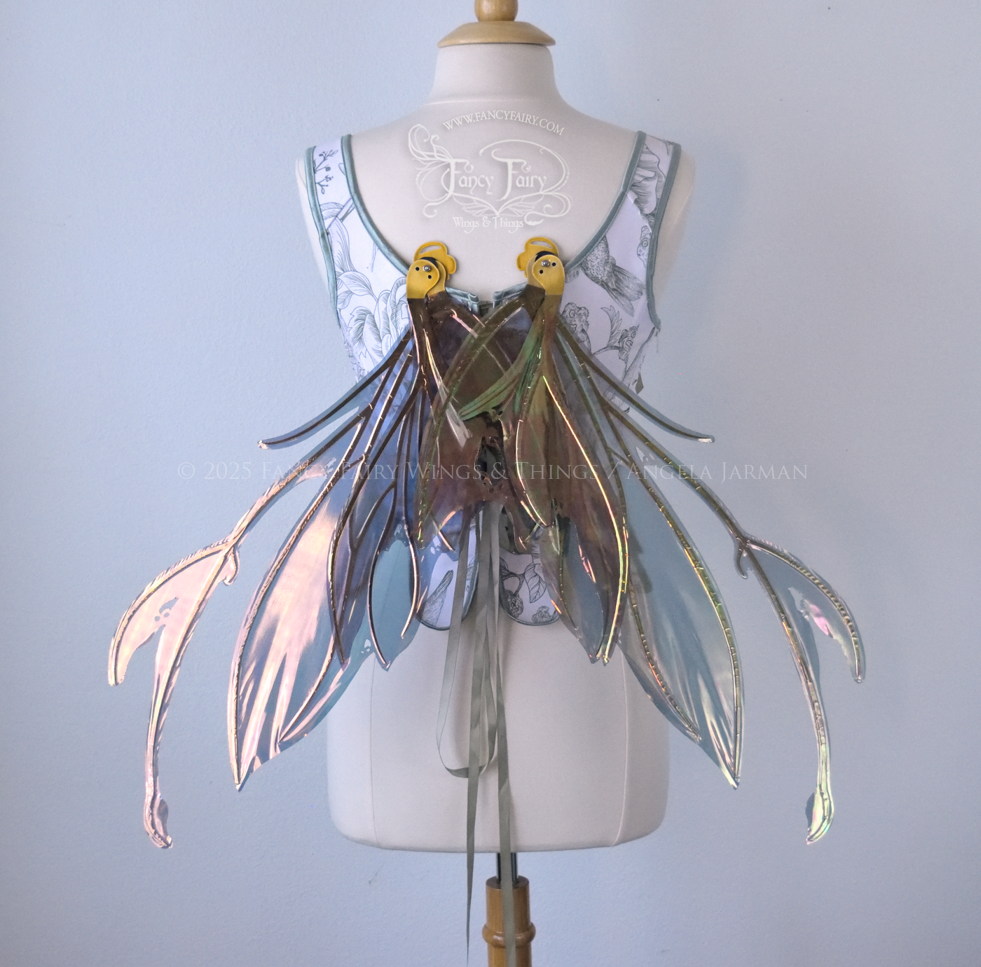 Dark orange / green & grey iridescent fairy wings with antennae and a spikey silhouette with tattered holes and gold veins, worn on a dress form, back view, in resting position