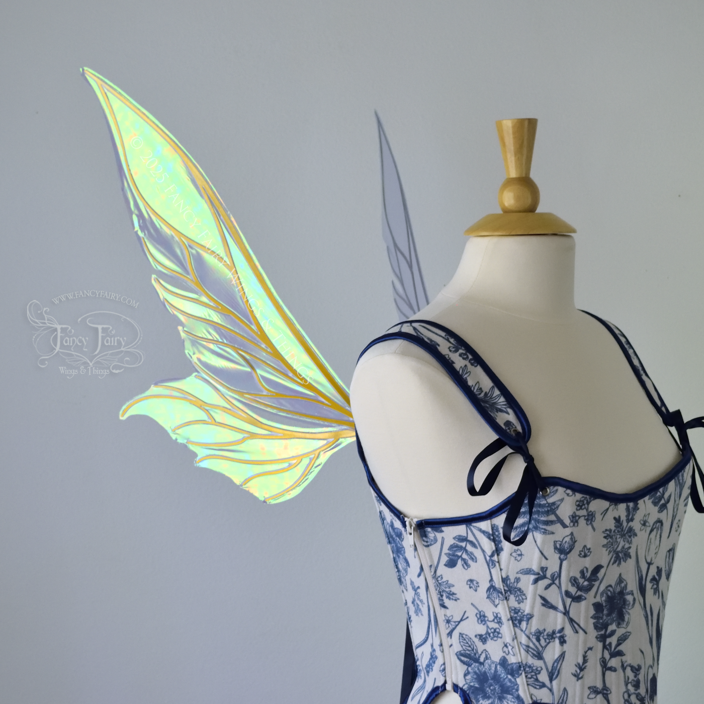 Iridescent blue / green fairy wings with elongated pointy upper panels and small leaf like lower panels, with gold veins, left side view
