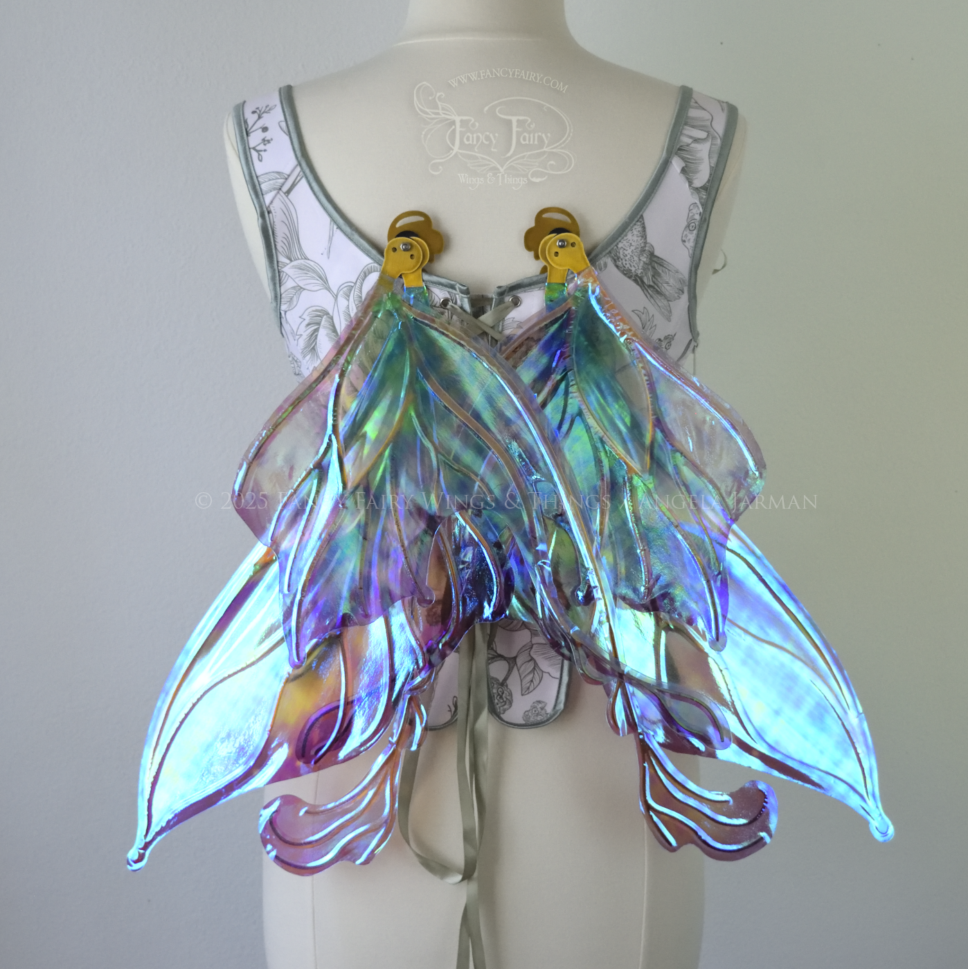 Iridescent & transparent purple & green fairy wings with gold veins and 2 swirling tails, worn on a dress form, back view, in resting position