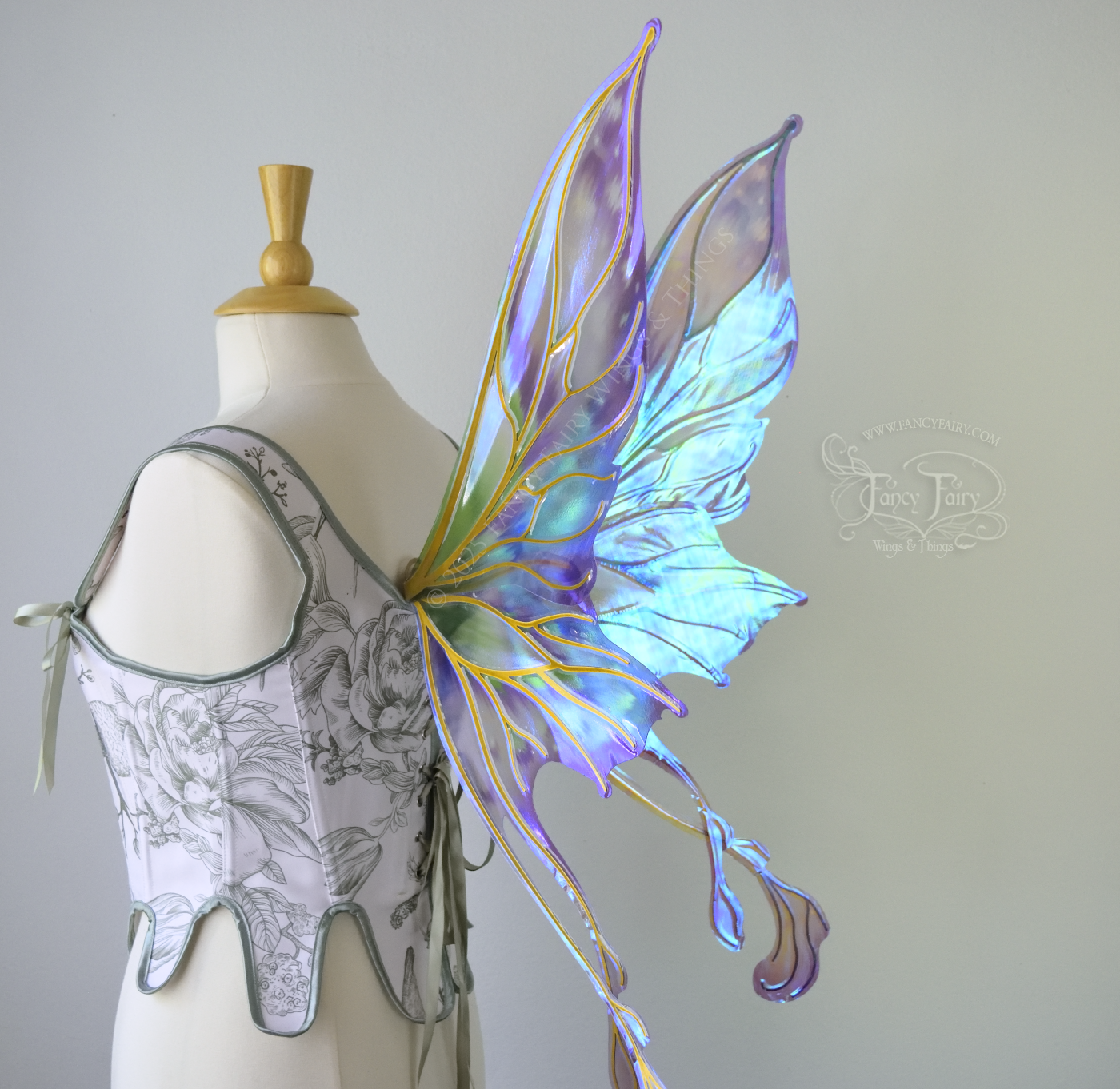 Iridescent & transparent purple & green fairy wings with gold veins and 2 swirling tails, worn on a dress form, right 3/4 back view