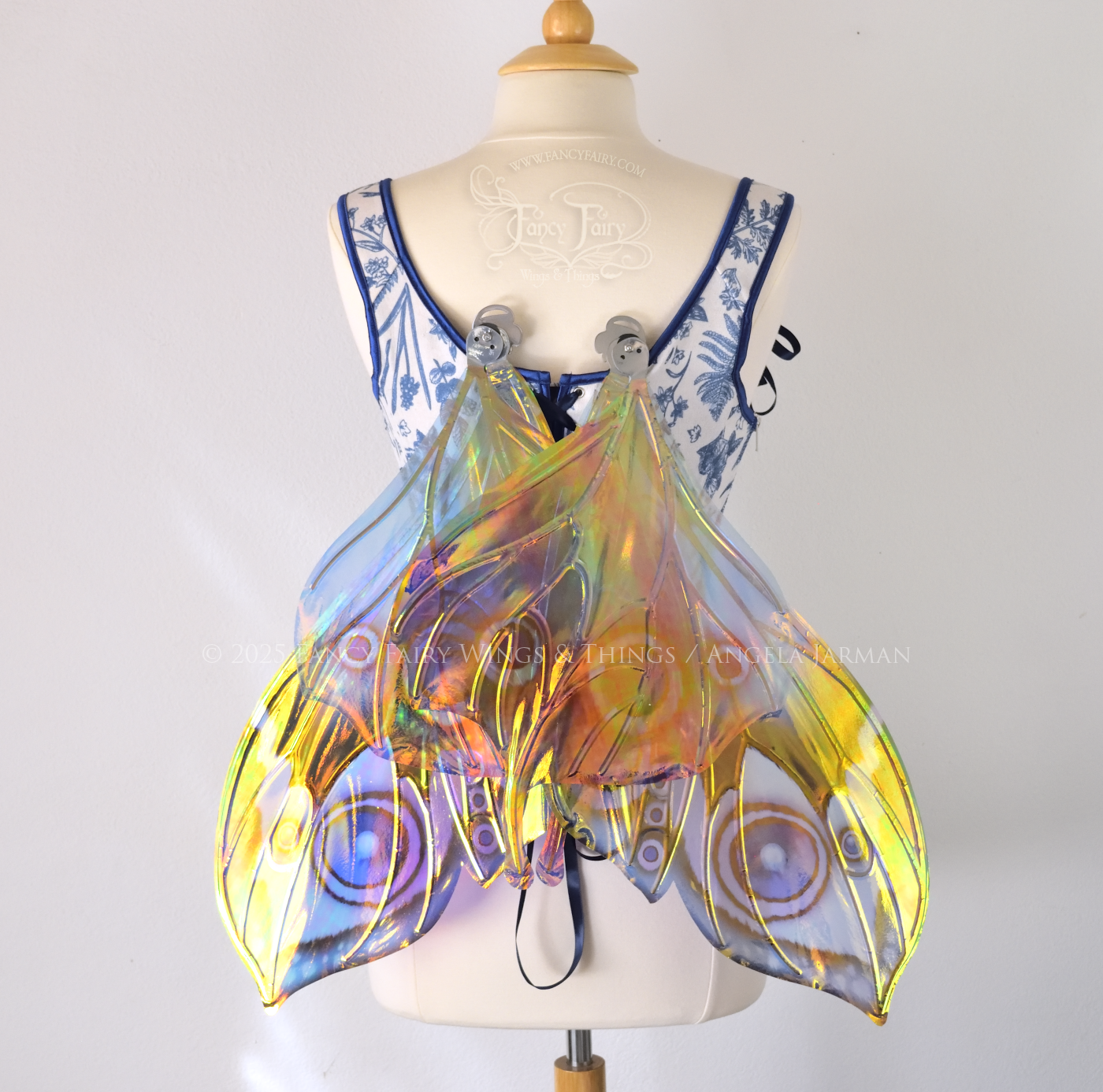 Blue iridescent butterfly shaped fairy wings with markings & 'eye' spots like the Buckeye butterfly, with silver veins, worn on a dress form, back view in resting position