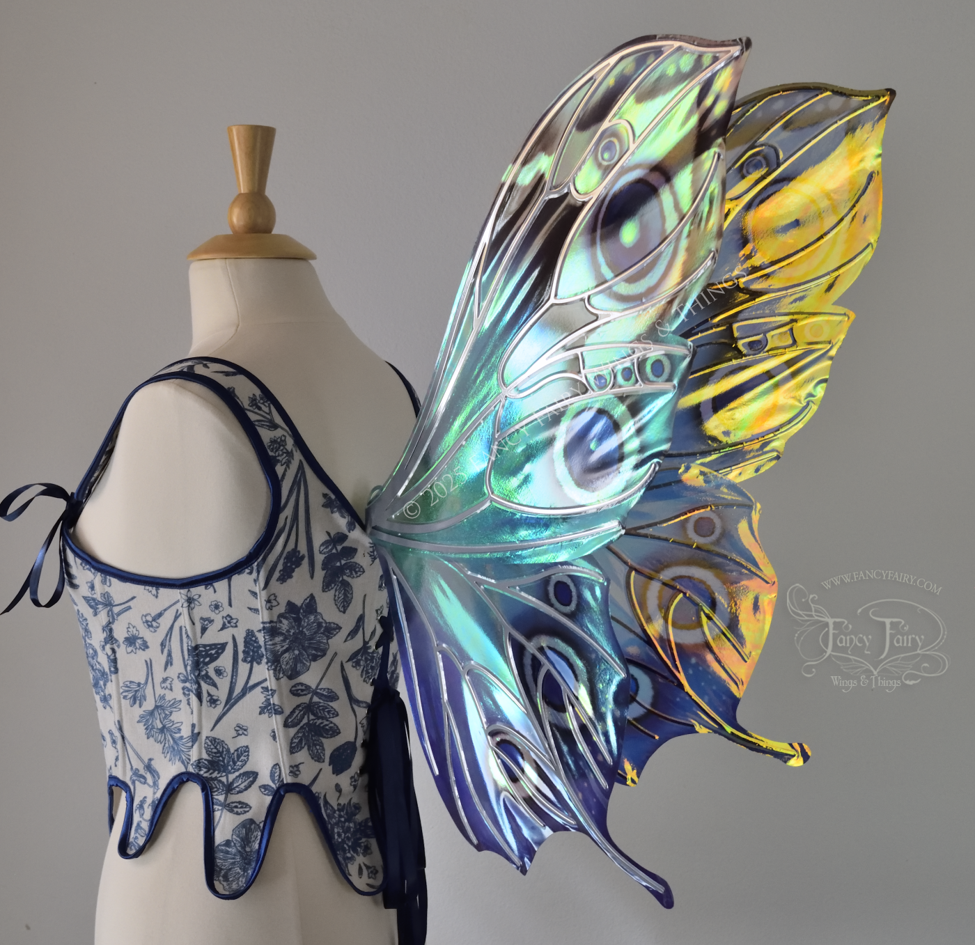 Blue iridescent butterfly shaped fairy wings with markings & 'eye' spots like the Buckeye butterfly, with silver veins, worn on a dress form, right 3/4 back side view