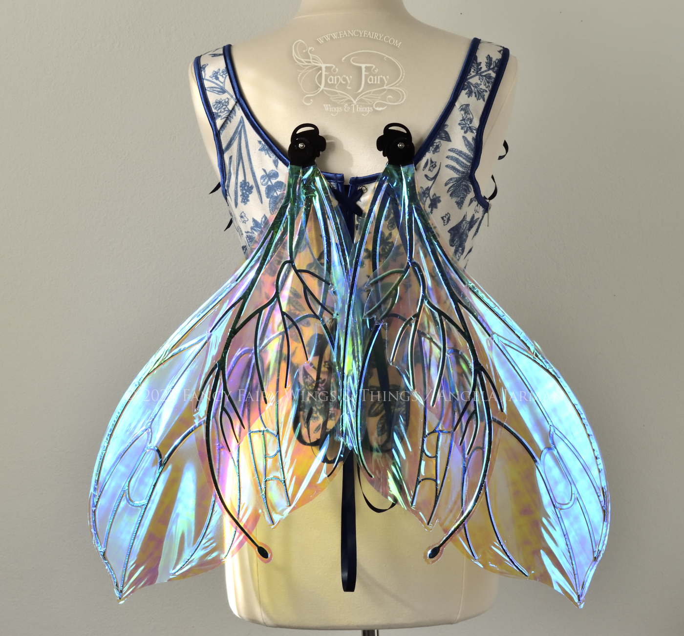 Large transparent iridescent blue fairy wings with black veins, worn on a dress form, back view, resting position