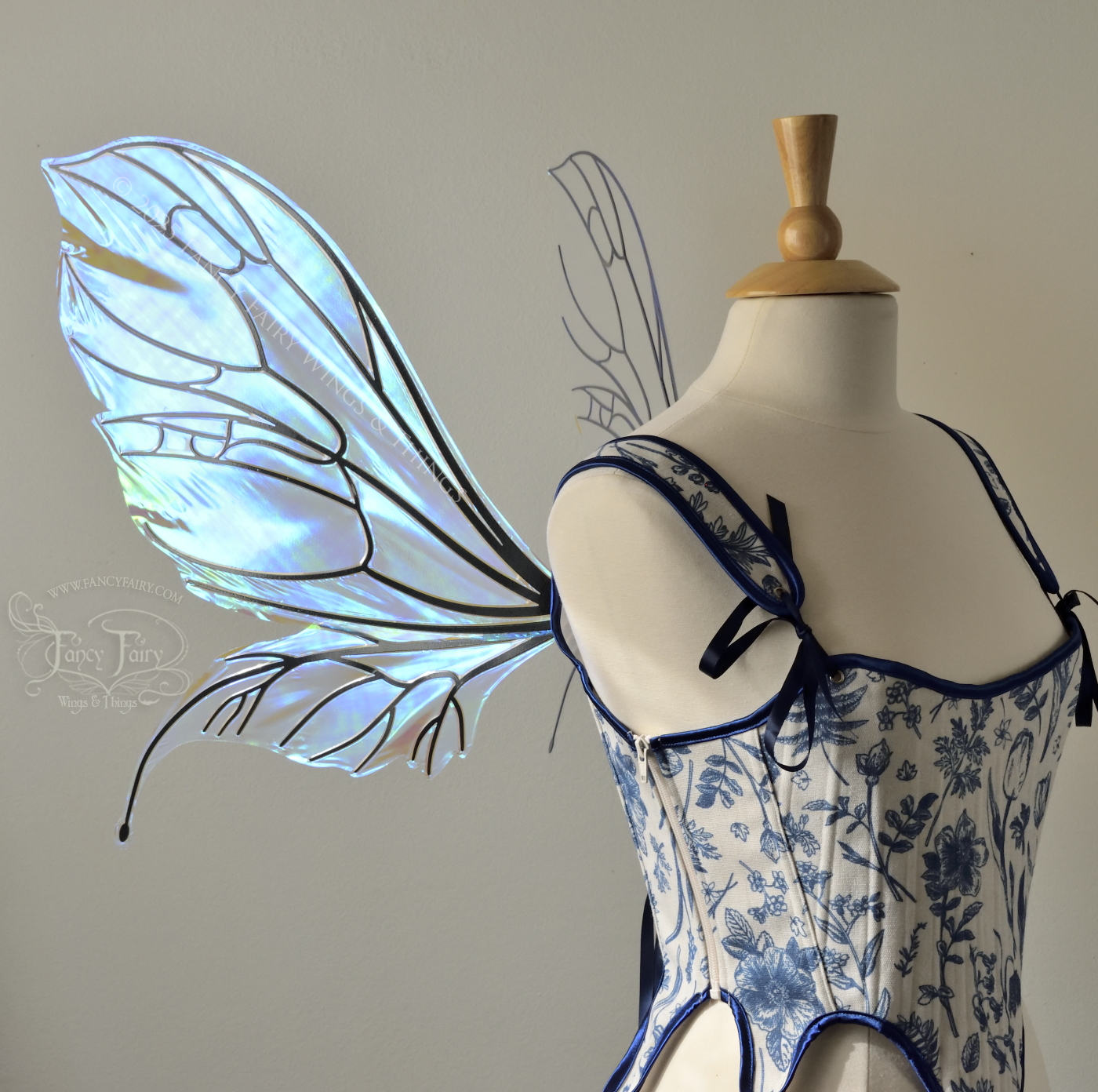 Large transparent iridescent blue fairy wings with black veins, worn on a dress form, left side view
