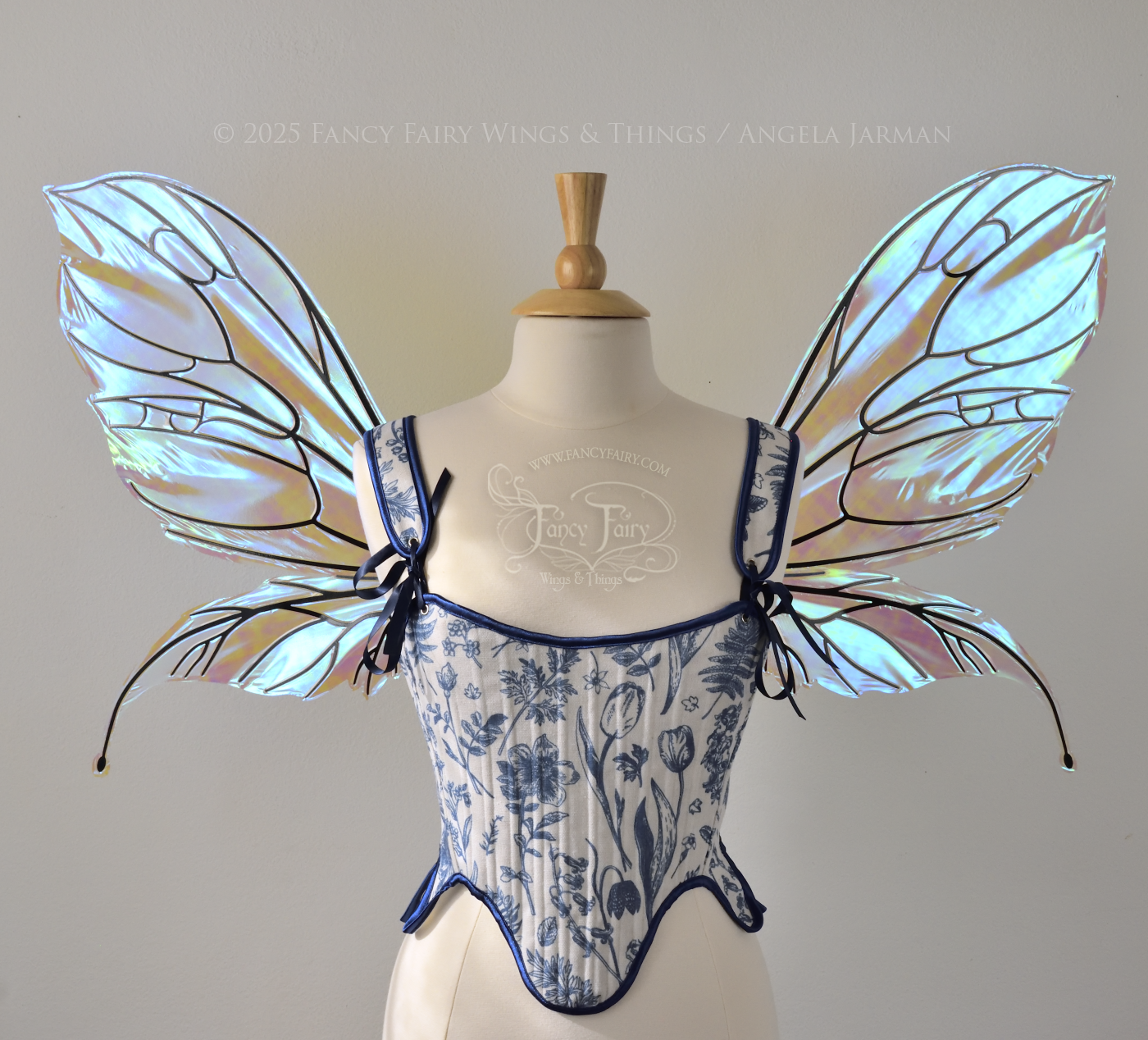 Large transparent iridescent blue fairy wings with black veins, worn on a dress form, front view