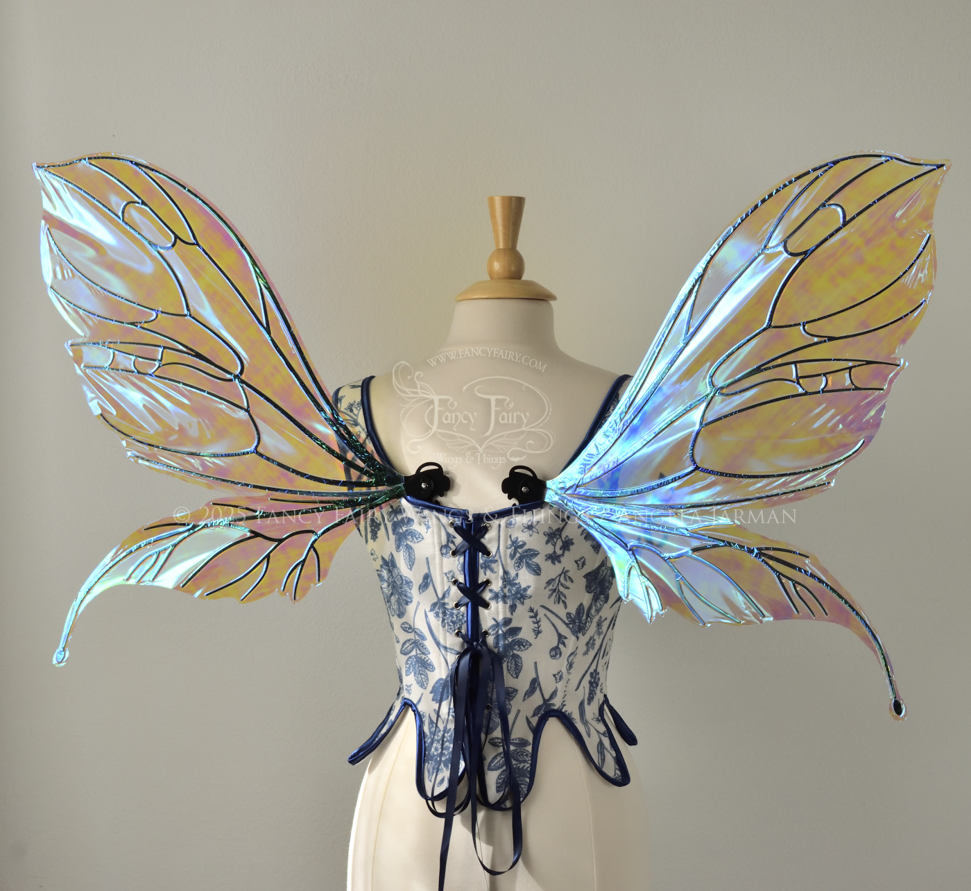 Large transparent iridescent blue fairy wings with black veins, worn on a dress form, back view