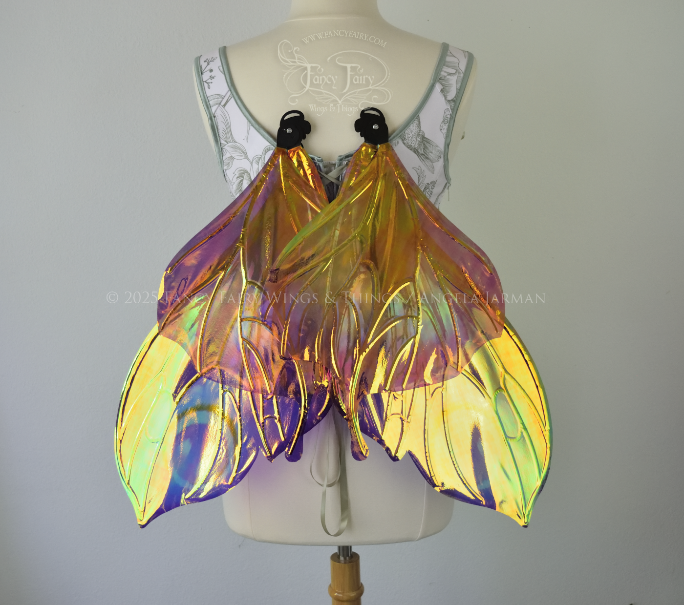 Iridescent fairy wings with a butterfly-like shape and short 'tails' in purples & blues with touches of pink & orange, back view, in resting position