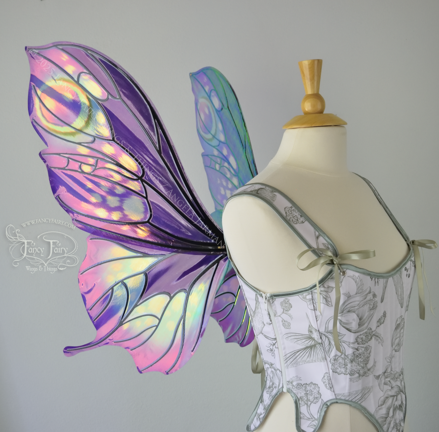 Iridescent fairy wings with a butterfly-like shape and short 'tails' in purples & blues with touches of pink & orange, left side view