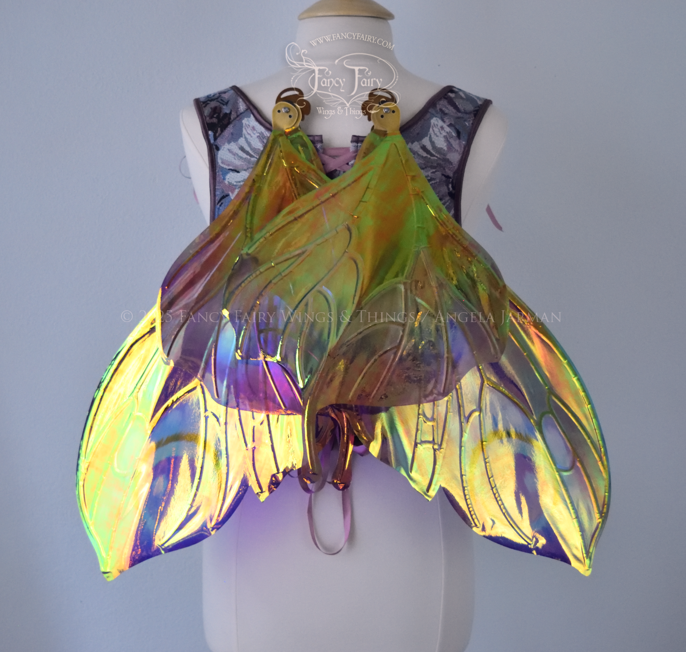 Large butterfly-esque iridescent fairy wings in shades of plum purple, blue and pink with art nouveau style gold veins, worn on a dress form, back view, in resting position
