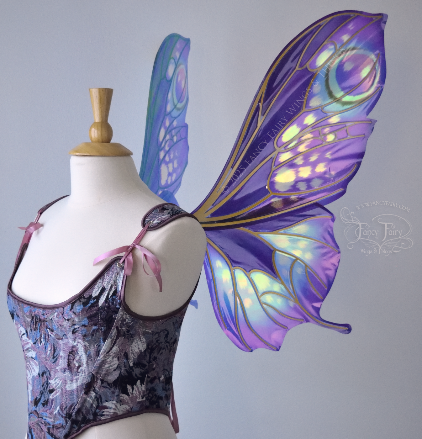 Large butterfly-esque iridescent fairy wings in shades of plum purple, blue and pink with art nouveau style gold veins, worn on a dress form, right side view
