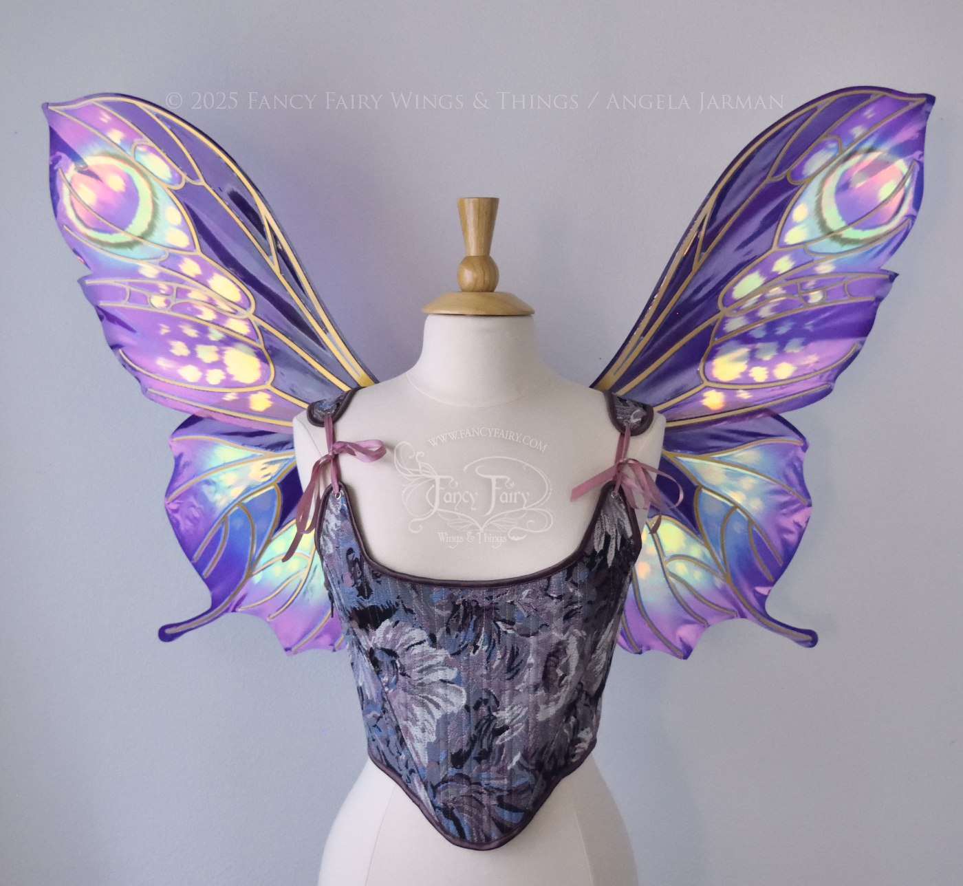 Large butterfly-esque iridescent fairy wings in shades of plum purple, blue and pink with art nouveau style gold veins, worn on a dress form, front view