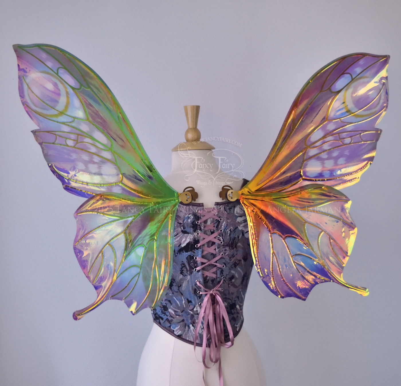 Large butterfly-esque iridescent fairy wings in shades of plum purple, blue and pink with art nouveau style gold veins, worn on a dress form, left side view