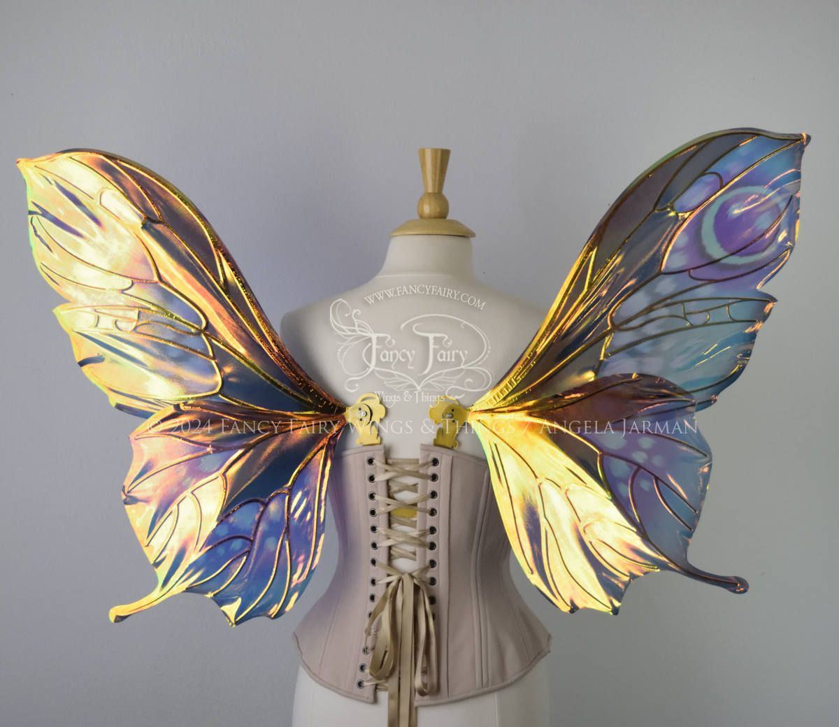 Back view of butterfly shaped iridescent wings in shades of teal with pink and lavender accents with gold veins, worn on a dressform