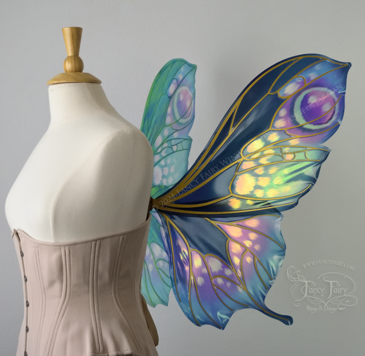 Right side view of butterfly shaped iridescent wings in shades of teal with pink and lavender accents with gold veins, worn on a dressform