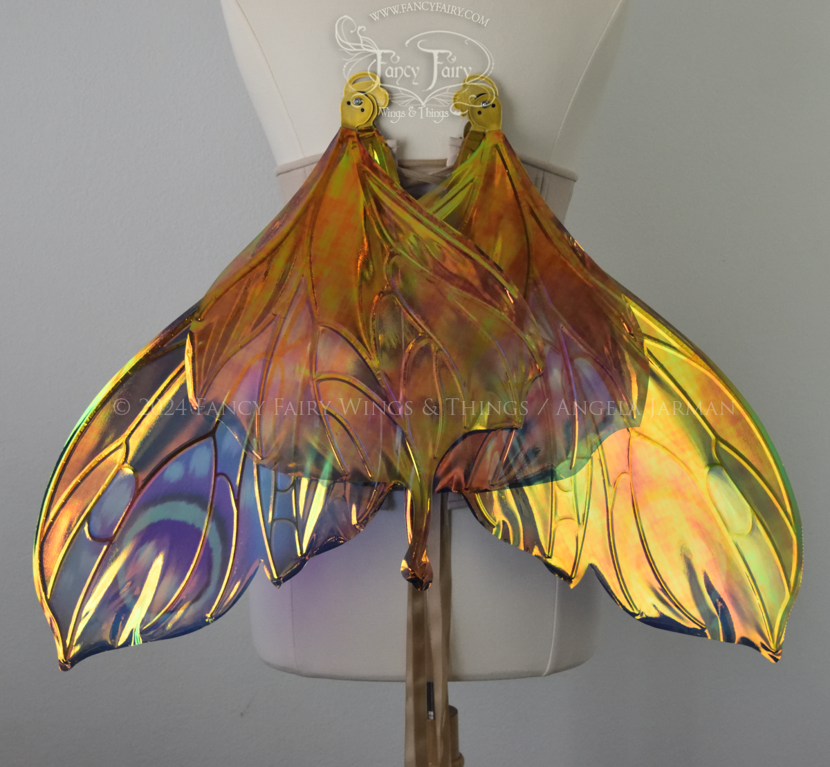 Back view of butterfly shaped iridescent wings in shades of teal with pink and lavender accents with gold veins, worn on a dressform in resting position