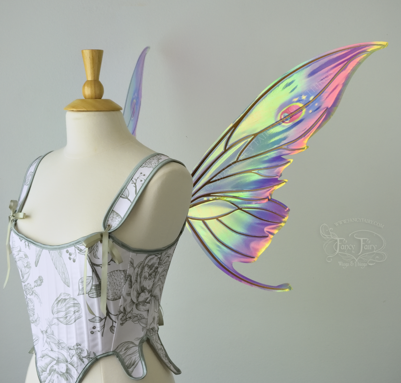 Iridescent rainbow fairy wings with elongated slightly downward curved tips on upper panels, and small tail that swoops up from bottom panels, worn on a dress form, right side view