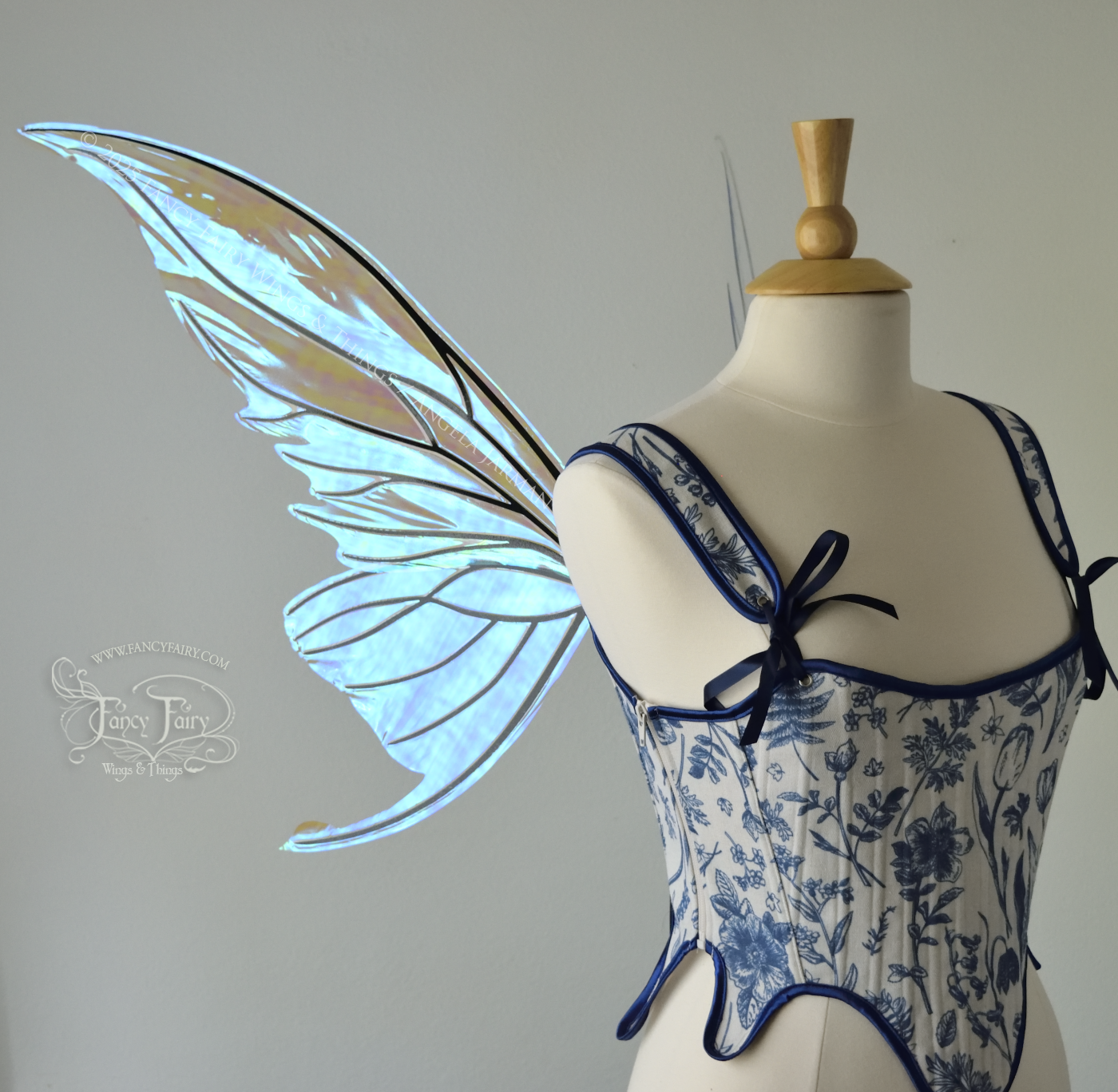 Iridescent transparent blue fairy wings with small tails & black veins worn on a dress form, left side view
