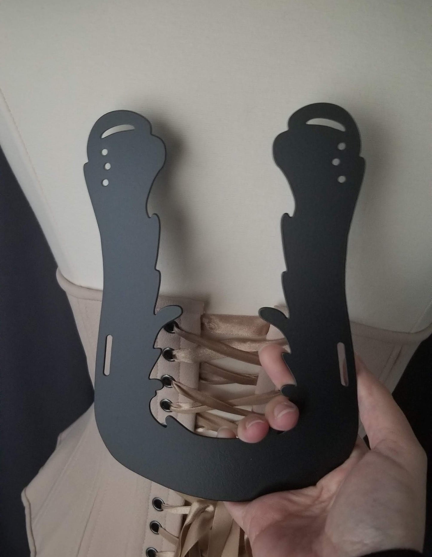 Extra large ornate back brace for convertible wings in black, with slots at the upper ends and bottom corners for ribbon to go thru and 3 holes at each end for the wing panels to screw onto, held in my hand