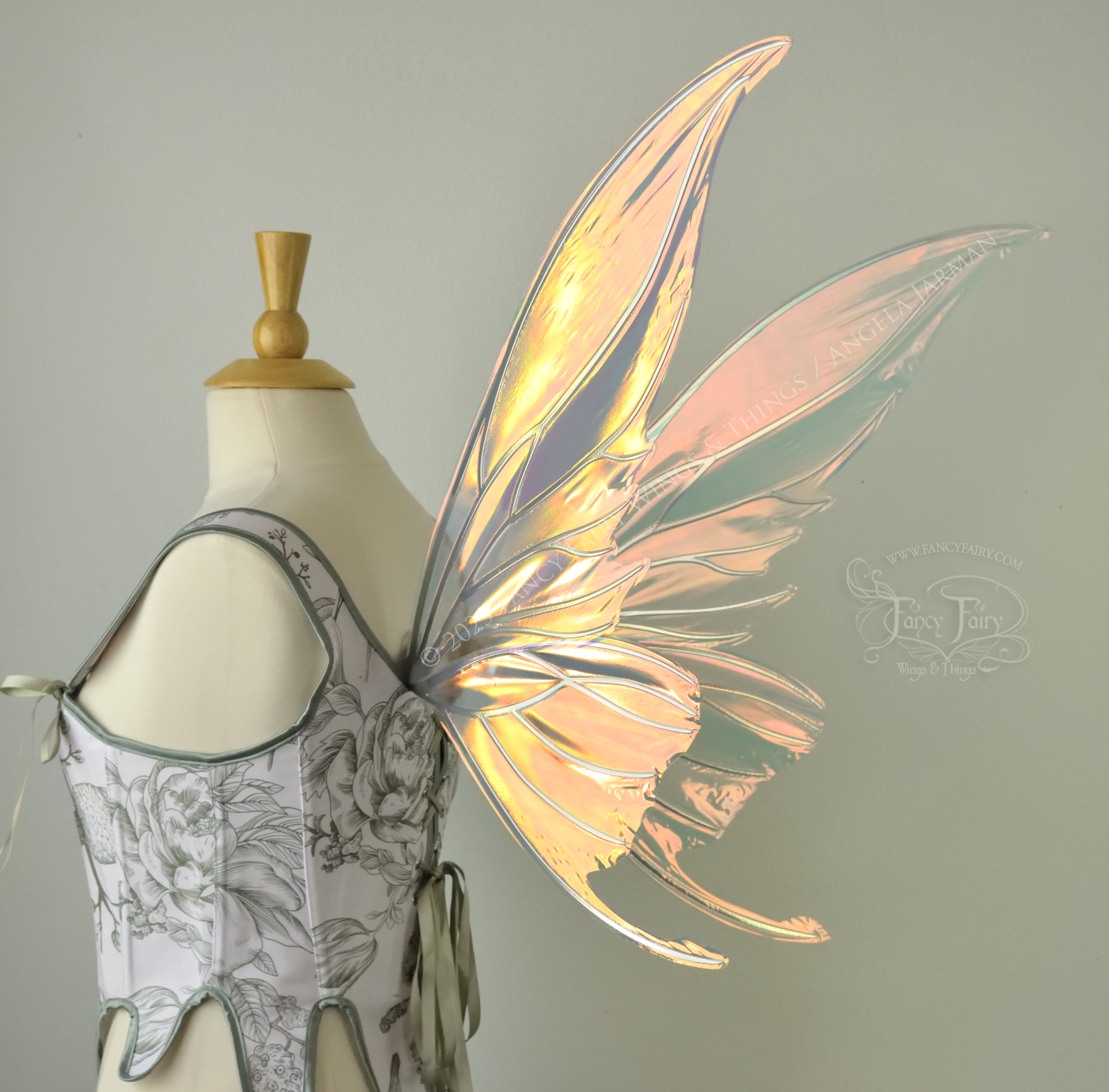 Iridescent pink & orange fairy wings with silver veins, and tails on the bottom panels that curve upwards, worn on a dress form, back 3/4 side view