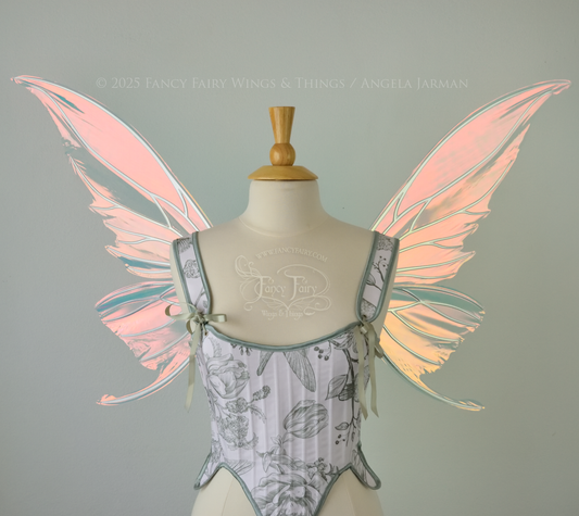 Iridescent pink & orange fairy wings with silver veins, and tails on the bottom panels that curve upwards, worn on a dress form, front view