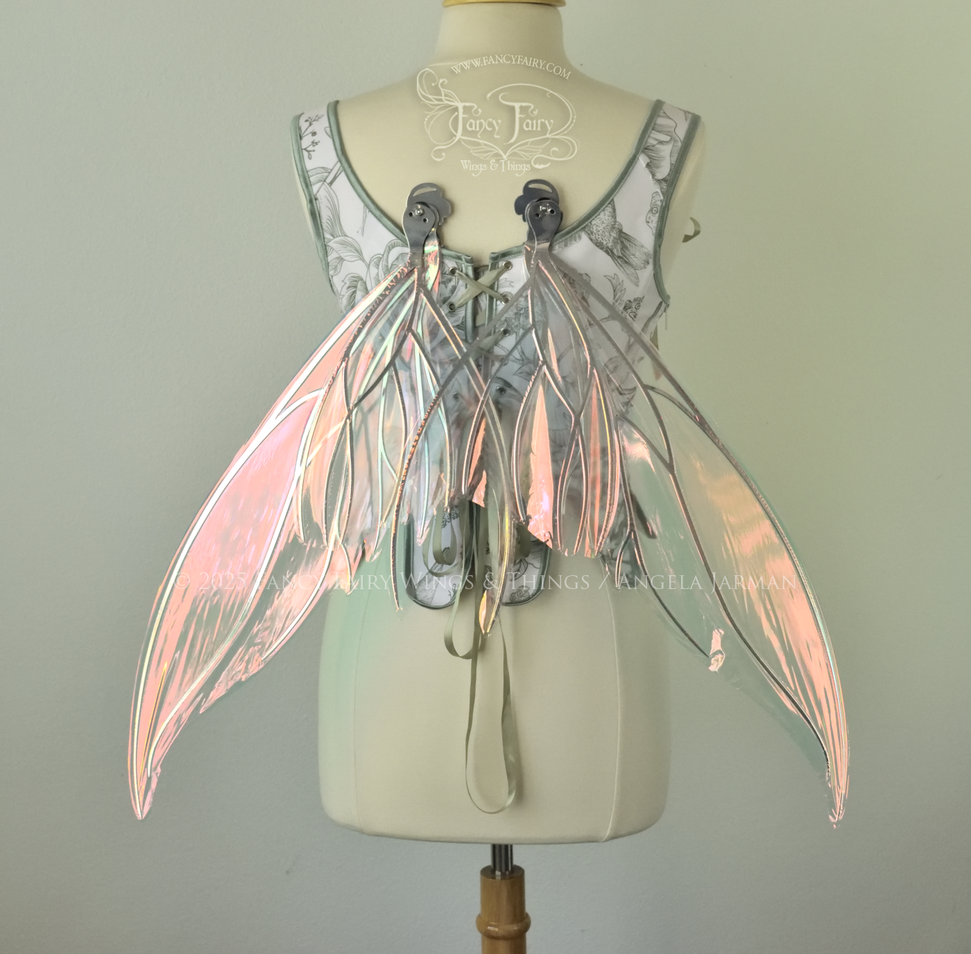 Iridescent pink & orange fairy wings with silver veins, and tails on the bottom panels that curve upwards, worn on a dress form, back view, in resting position