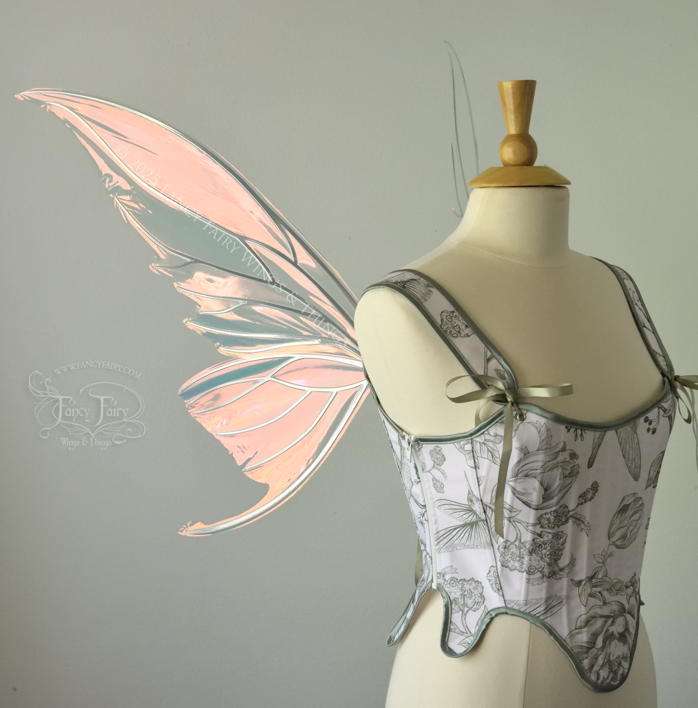 Iridescent pink & orange fairy wings with silver veins, and tails on the bottom panels that curve upwards, worn on a dress form, left side view