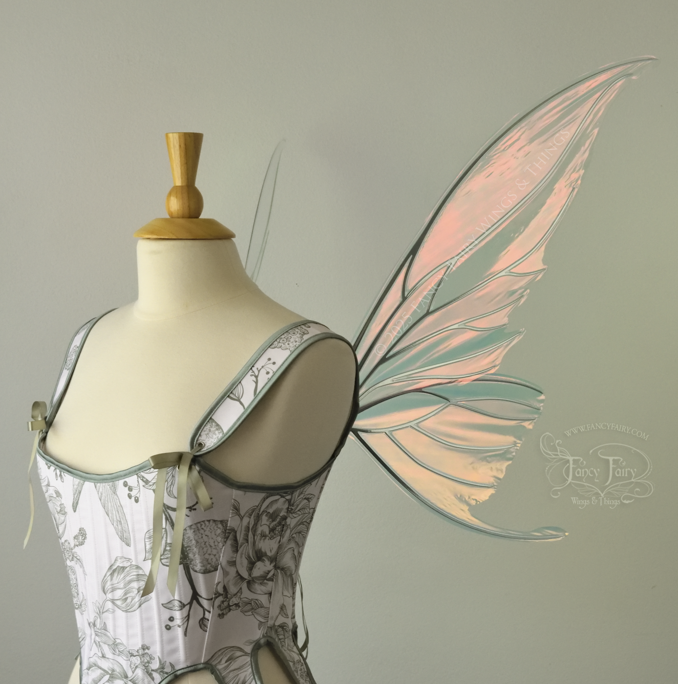Iridescent pink & orange fairy wings with silver veins, and tails on the bottom panels that curve upwards, worn on a dress form, right side view