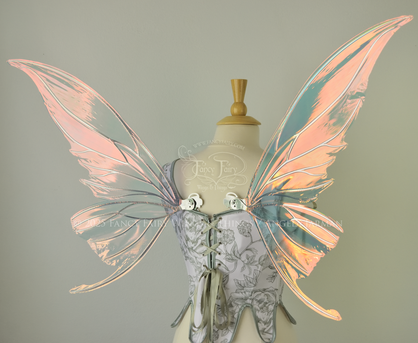 Iridescent pink & orange fairy wings with silver veins, and tails on the bottom panels that curve upwards, worn on a dress form, back view
