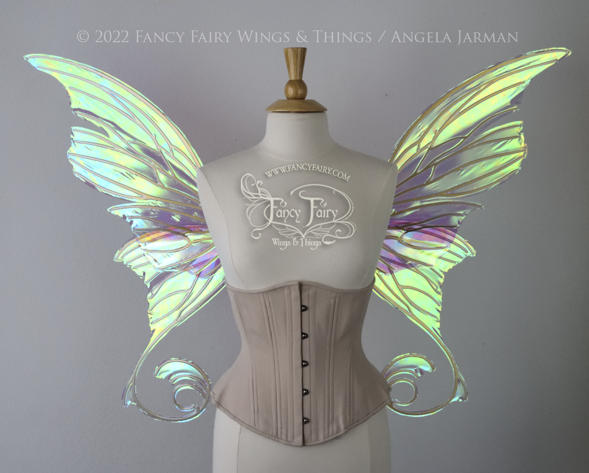 Front view of a dress form wearing an underbust corset & large green iridescent fairy wings with lots of intricate gold veins, some have 'thorns'. Upper panels curve slightly downwards along top edge with pointy tips, bottom panels have tails