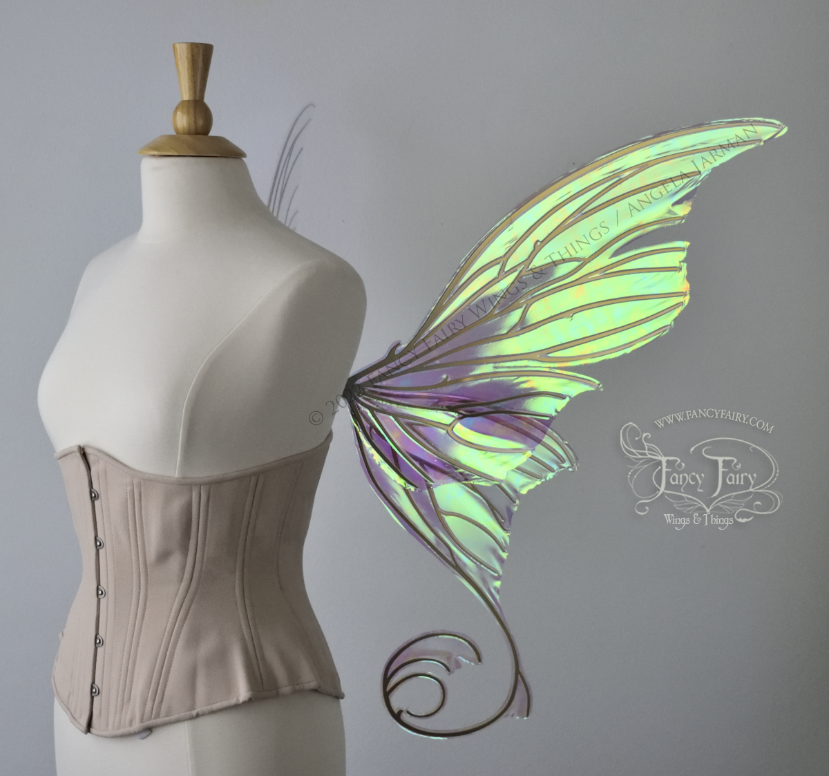 Right side view of a dress form wearing an underbust corset & large green iridescent fairy wings with lots of intricate gold veins, some have 'thorns'. Upper panels curve slightly downwards along top edge with pointy tips, bottom panels have tails