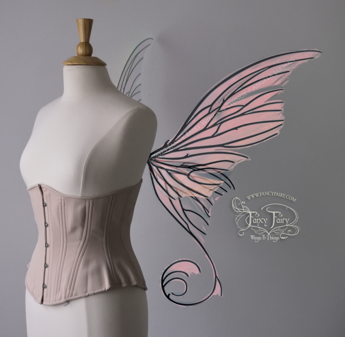 Right side view of an ivory dress form wearing an alabaster underbust corset and large pink / orange iridescent fairy wings with lots of intricate black veins, some have 'thorns'. Upper panels curve slightly downwards along top edge with pointy tips, bottom panels have tails