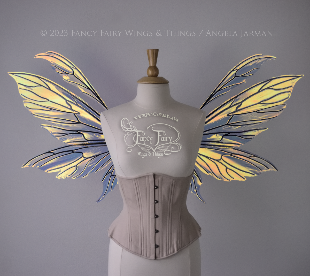 Transparent iridescent fairy wings with 3 panels on each side and antennae with black veins, worn on a dress form, front view