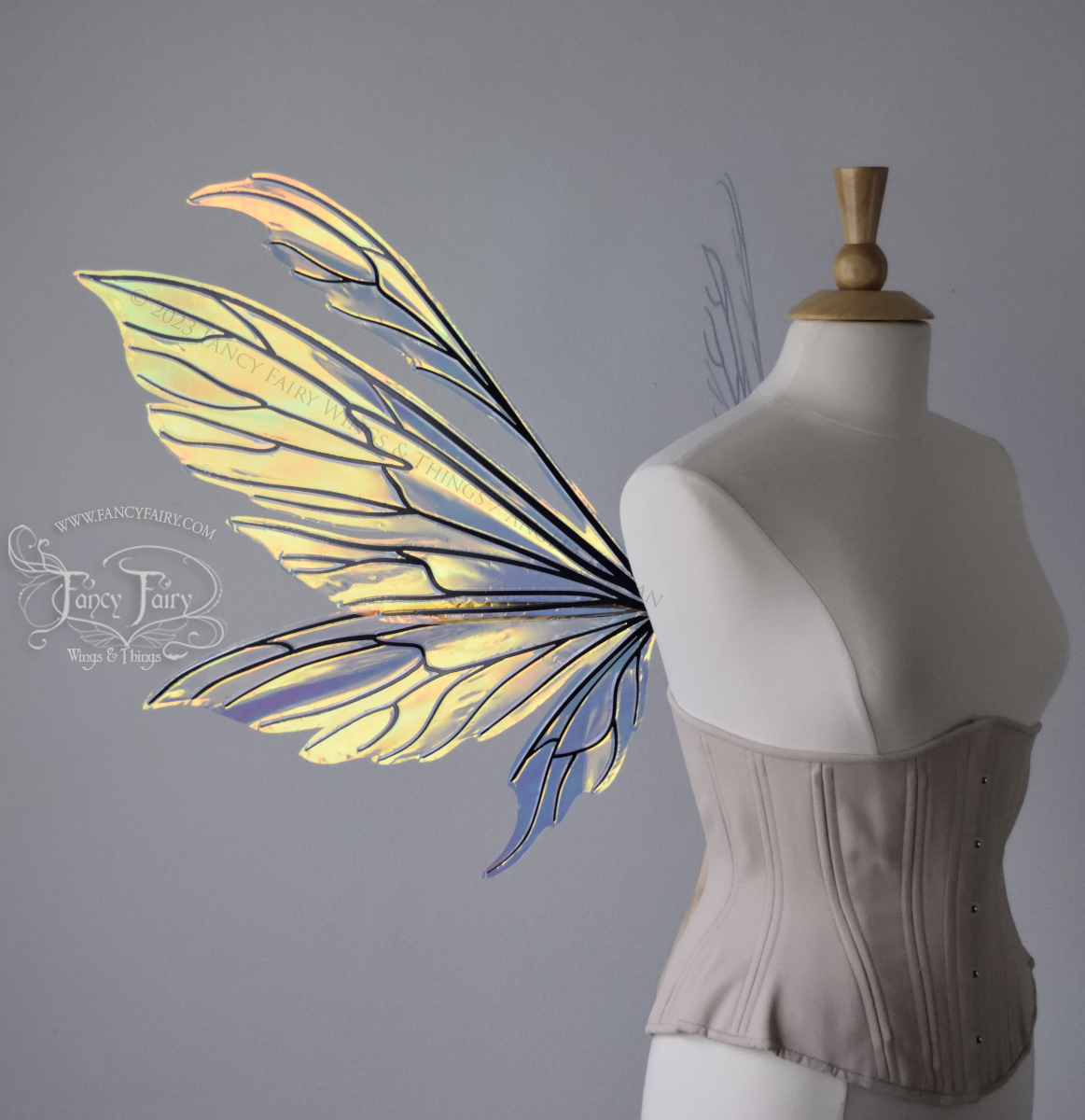 Transparent iridescent fairy wings with 3 panels on each side and antennae with black veins, worn on a dress form, left side view