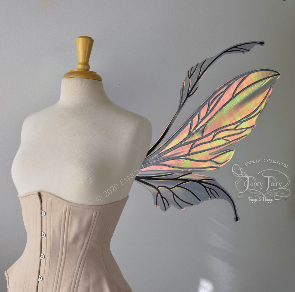 Right side view of dress form wearing an underbust corset and large iridescent orange / green fairy wings featuring antennae along the top. The upper panels are elongated with semi-pointed tips, the lower panels are smaller with slender tips that curve downward. The veins are black
