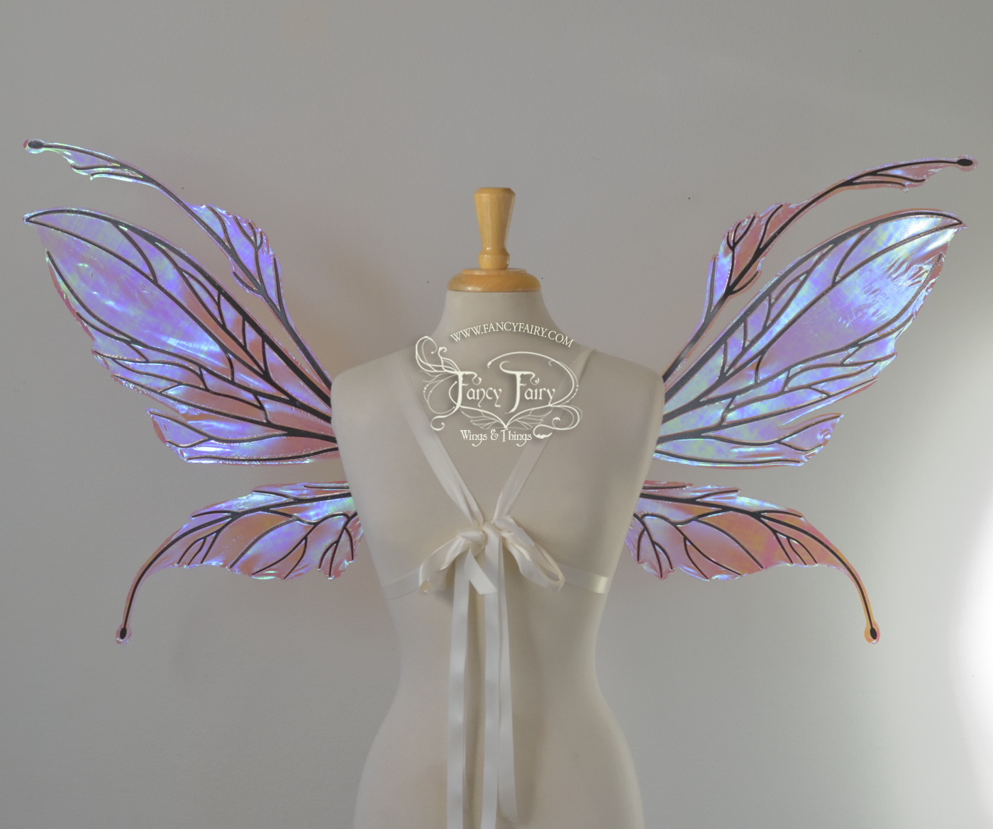 Front view of dress form wearing an underbust corset and large iridescent pinkish lavender fairy wings featuring antennae along the top. The upper panels are elongated with semi-pointed tips, the lower panels are smaller with slender tips that curve downward. The veins are black