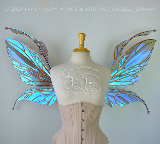 Large iridescent blue/violet fairy wings featuring antennae along the top. Upper panels are elongated with semi-pointed tips, lower panels are smaller with slender tips curving downward, worn on a dress form, front view