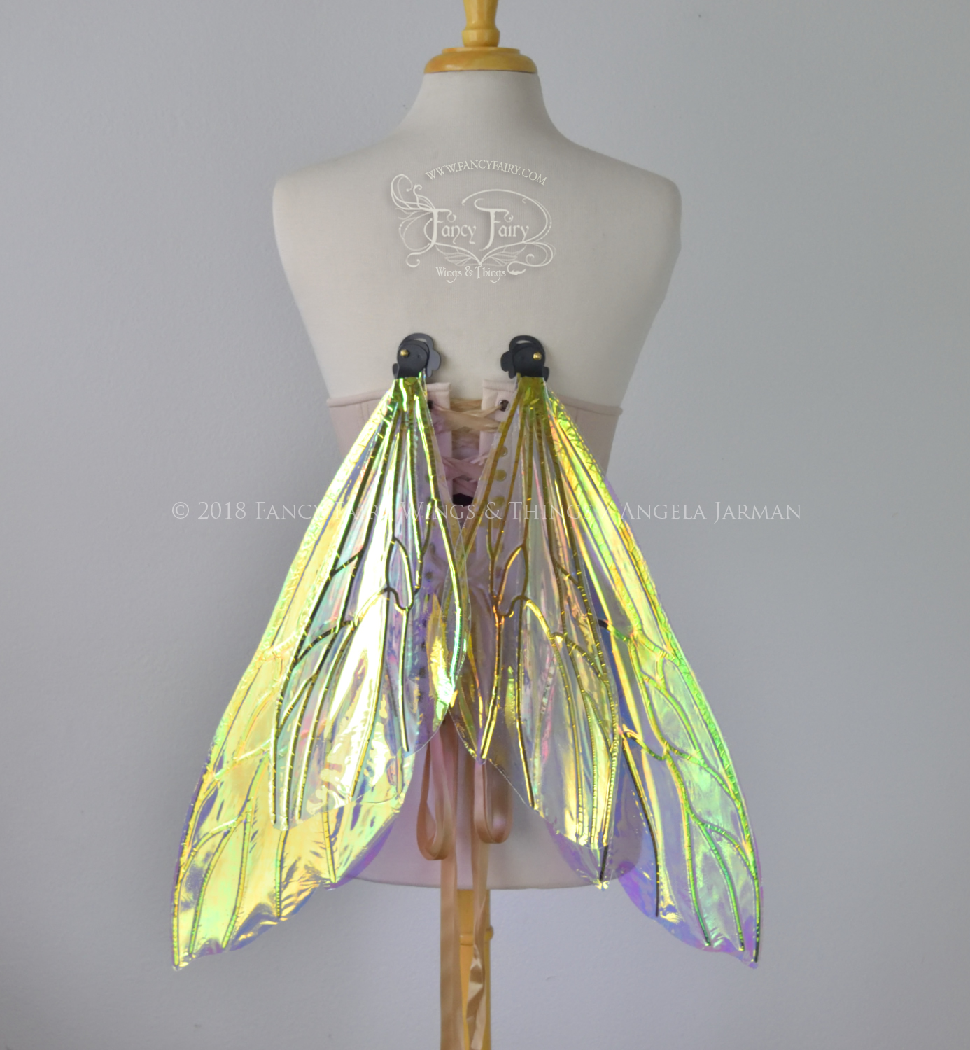 Transparent iridescent wasp-like fairy wings with black veins worn on a dress form, back view, in resting position