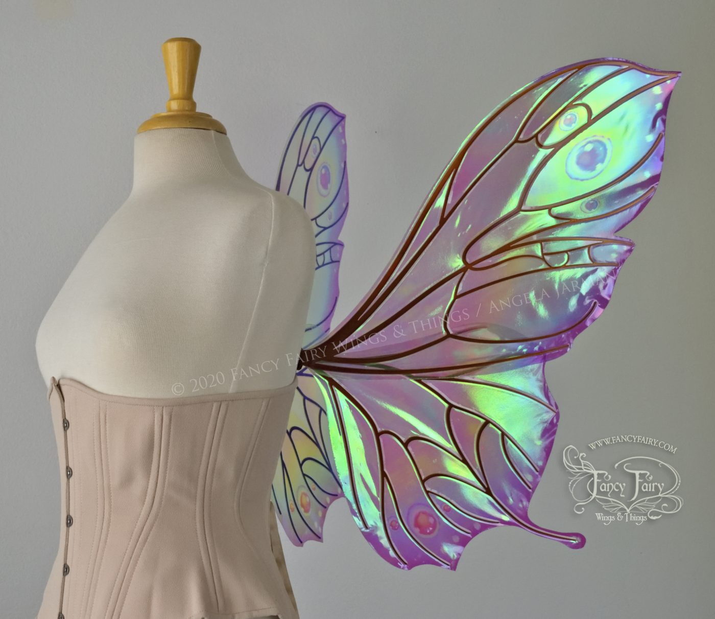 Bright rainbow colored iridescent fairy wings in a butterfly sort of shape with small 'tails' on the bottom panels curving slightly up, with copper veins. Worn on a dress form, right side view