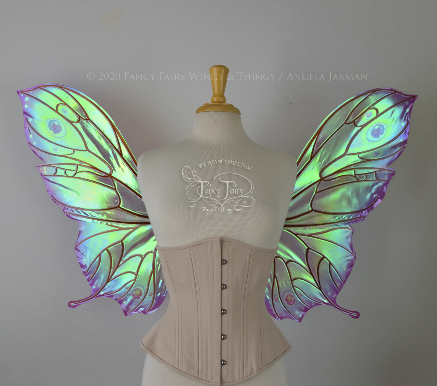 Bright rainbow colored iridescent fairy wings in a butterfly sort of shape with small 'tails' on the bottom panels curving slightly up, with copper veins. Worn on a dress form, front view