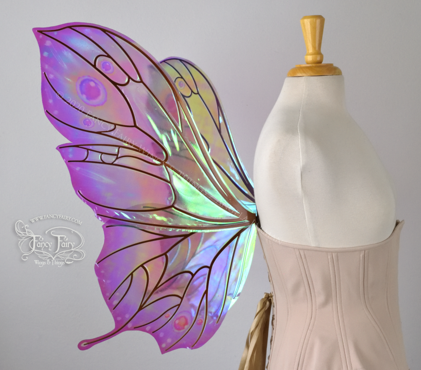 Bright rainbow colored iridescent fairy wings in a butterfly sort of shape with small 'tails' on the bottom panels curving slightly up, with copper veins. Worn on a dress form, left side view