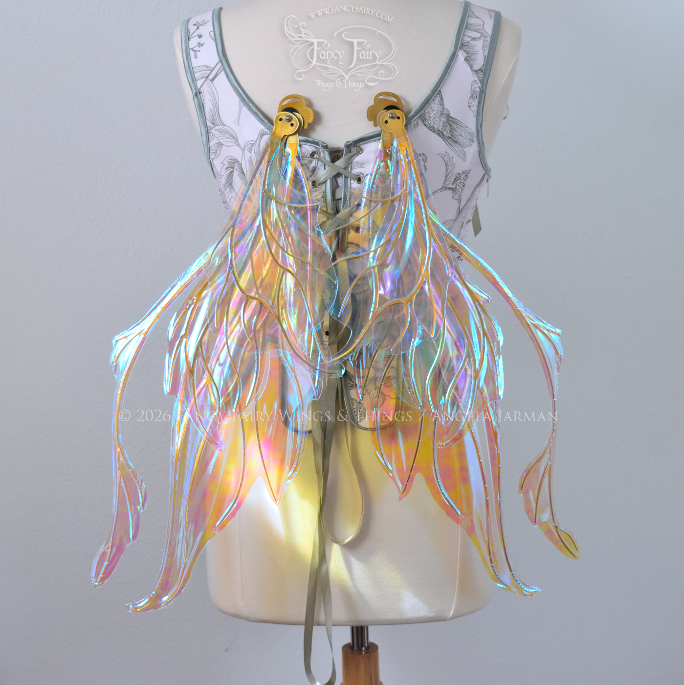 Transparent & iridescent fairy wings with blue shine and gold veins have antennae & upward curving tips, worn on a dress form, back view in resting position