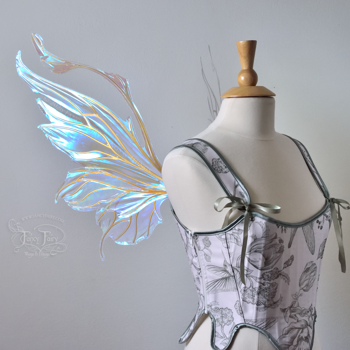 Transparent & iridescent fairy wings with blue shine and gold veins have antennae & upward curving tips, worn on a dress form, left side view