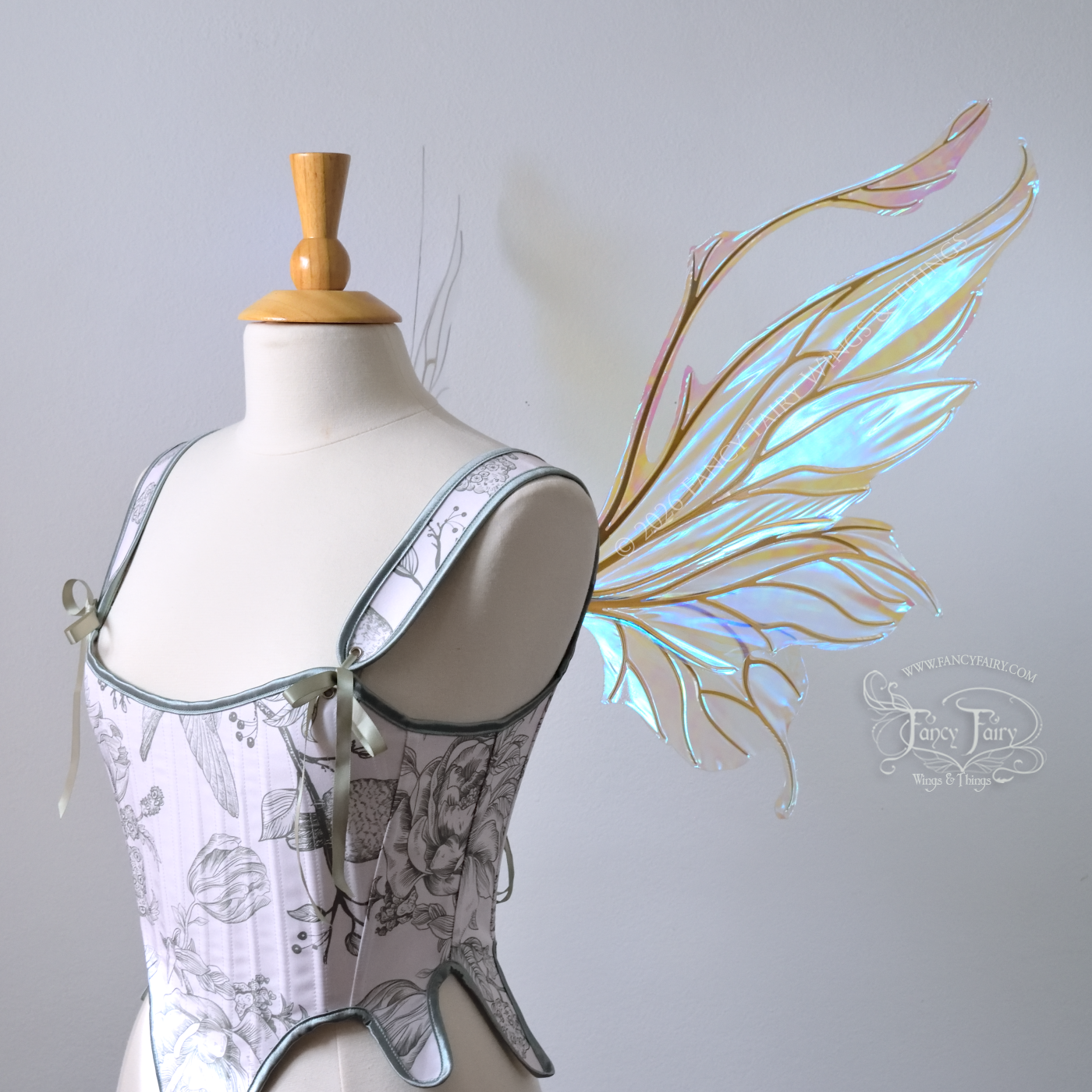 Transparent & iridescent fairy wings with blue shine and gold veins have antennae & upward curving tips, worn on a dress form, right side view
