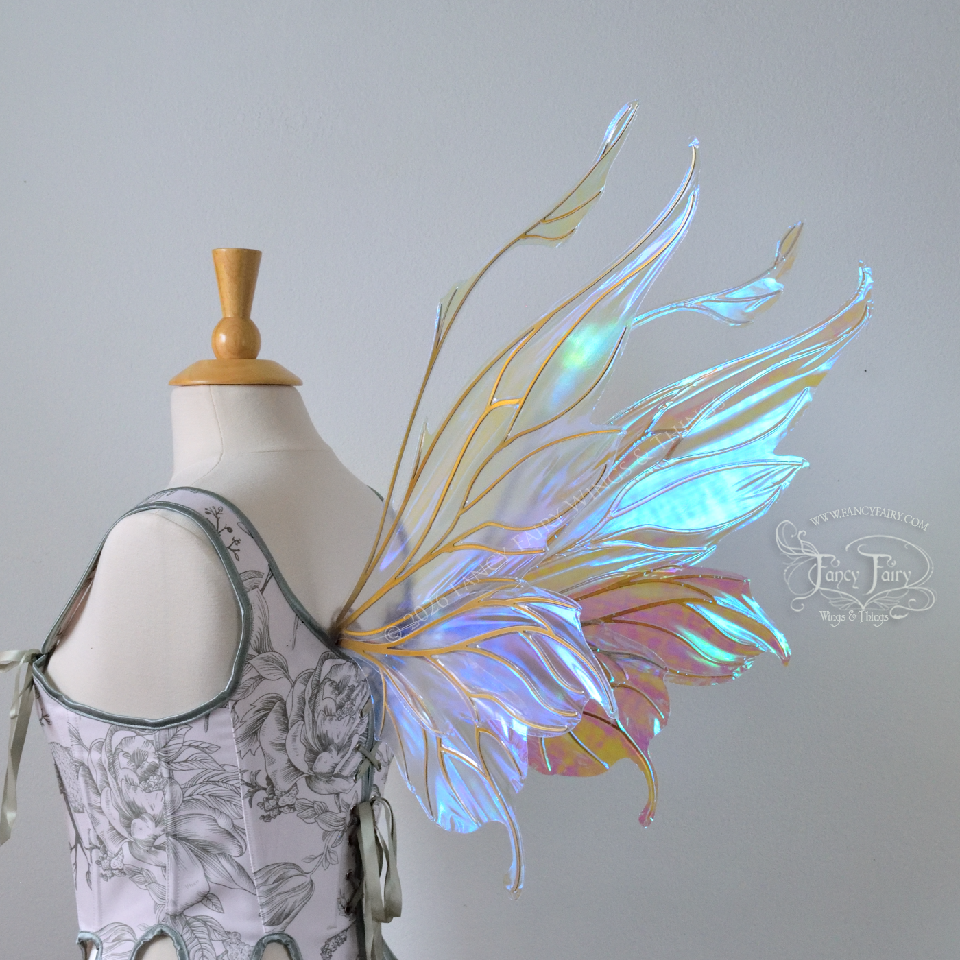 Transparent & iridescent fairy wings with blue shine and gold veins have antennae & upward curving tips, worn on a dress form, back 3/4 view