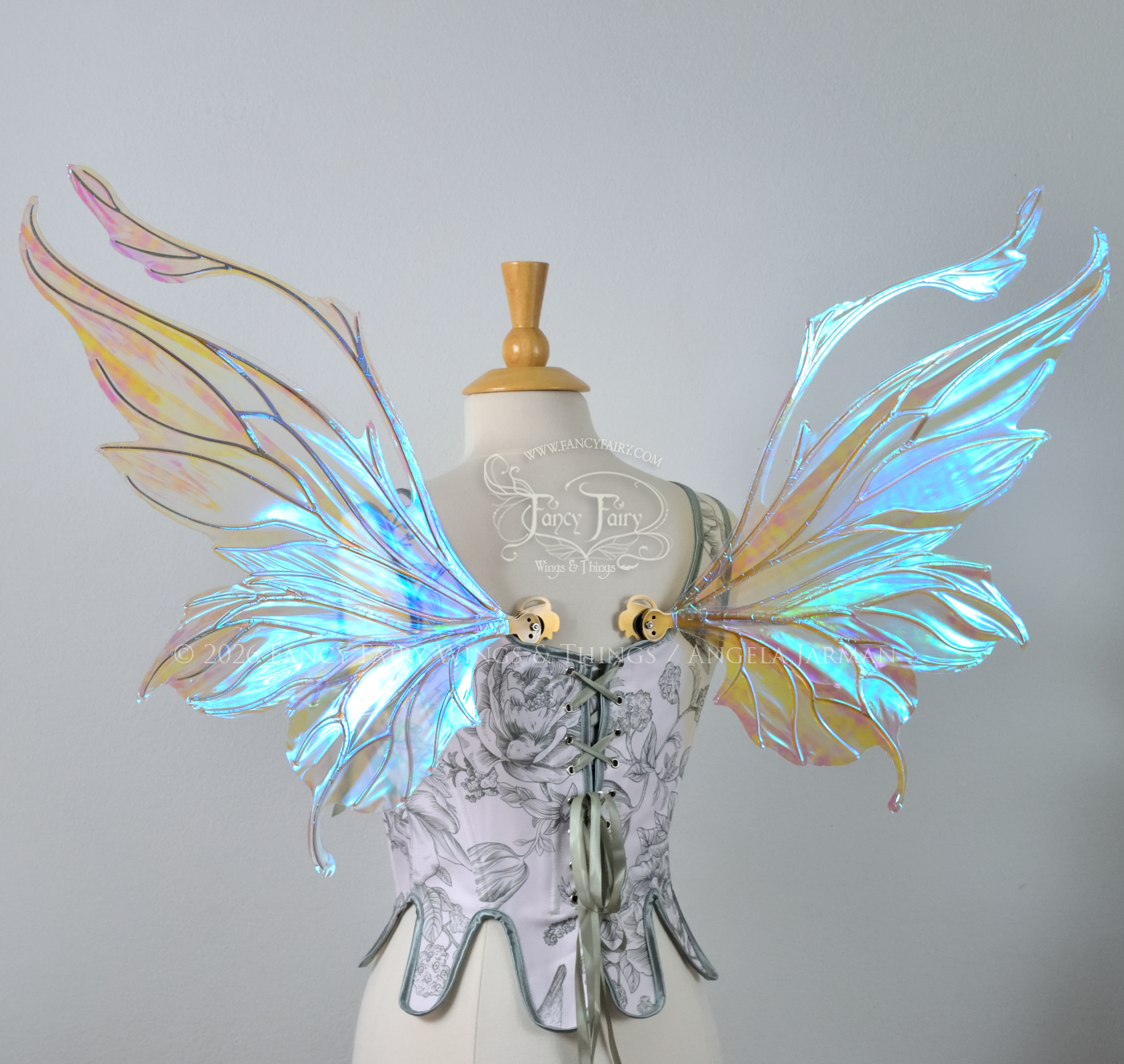 Transparent & iridescent fairy wings with blue shine and gold veins have antennae & upward curving tips, worn on a dress form, back view