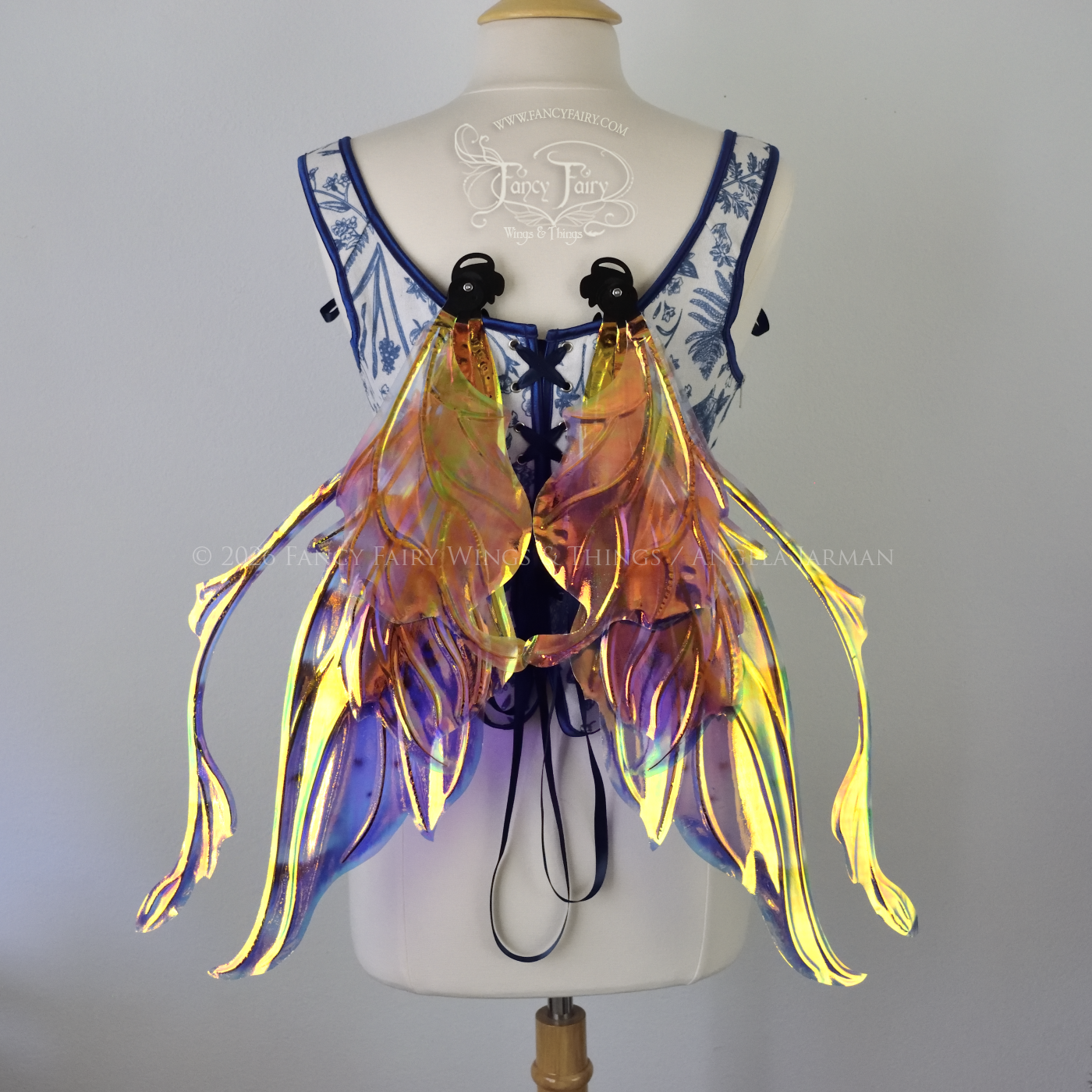 Iridescent fairy wings in purple, pink, teal and black have wavy antennae & upward curving tips, worn on a dress form, back view, in resting position
