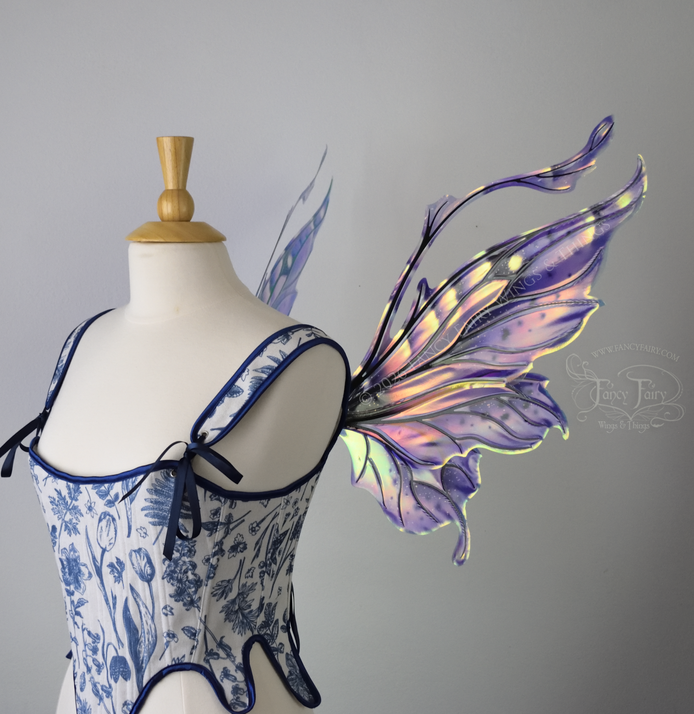 Iridescent fairy wings in purple, pink, teal and black have wavy antennae & upward curving tips, worn on a dress form, right side view
