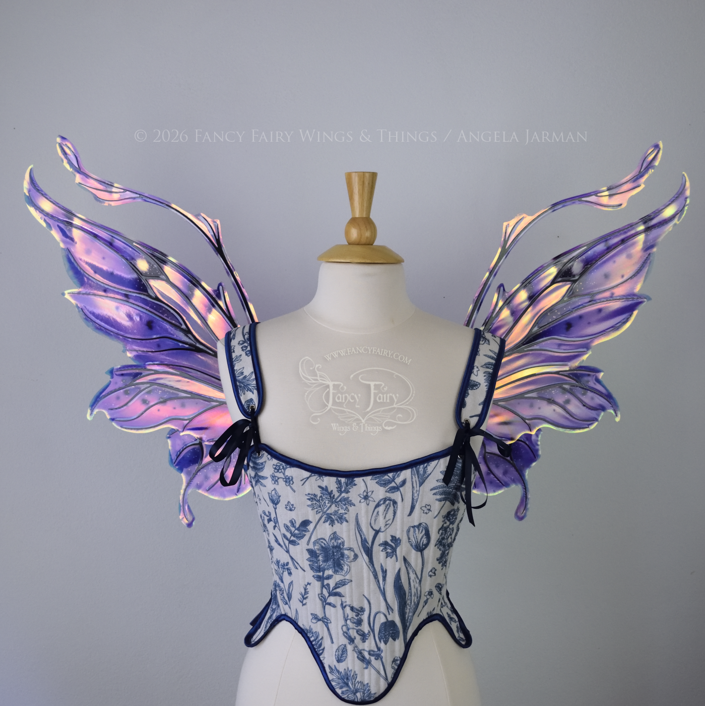 Iridescent fairy wings in purple, pink, teal and black have wavy antennae & upward curving tips, worn on a dress form, front view