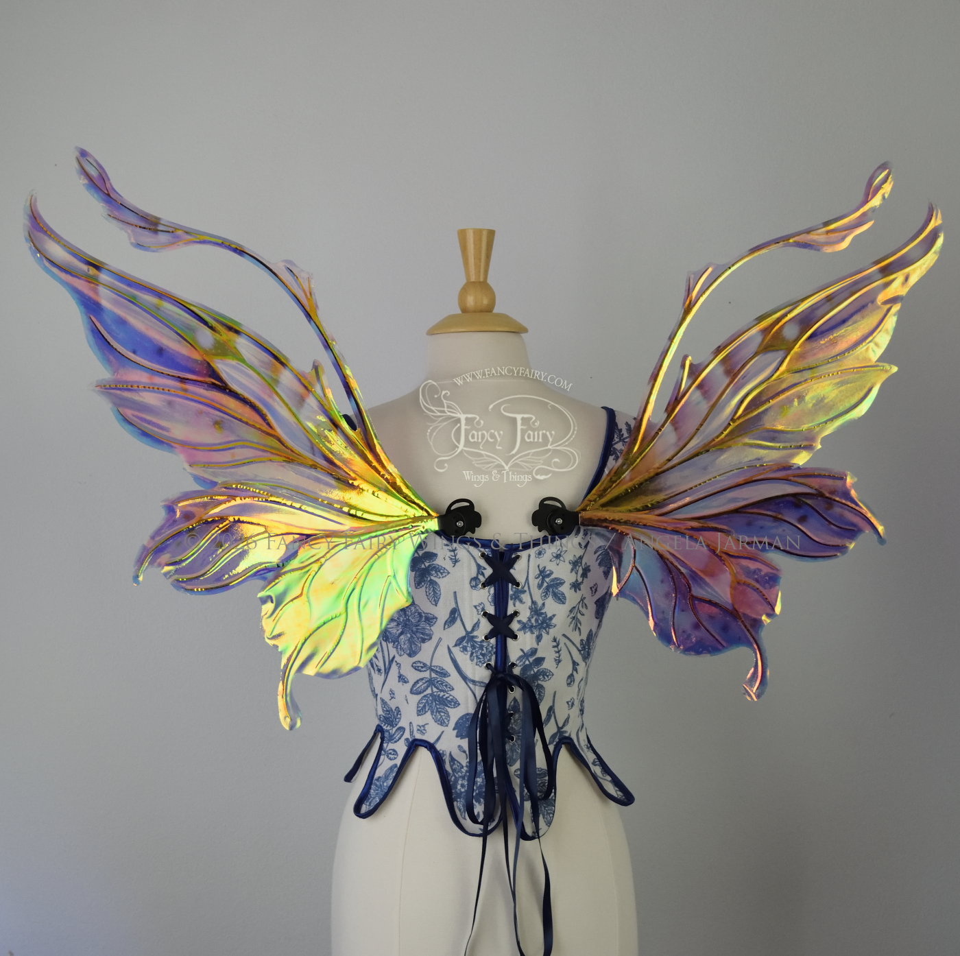 Iridescent fairy wings in purple, pink, teal and black have wavy antennae & upward curving tips, worn on a dress form, back view